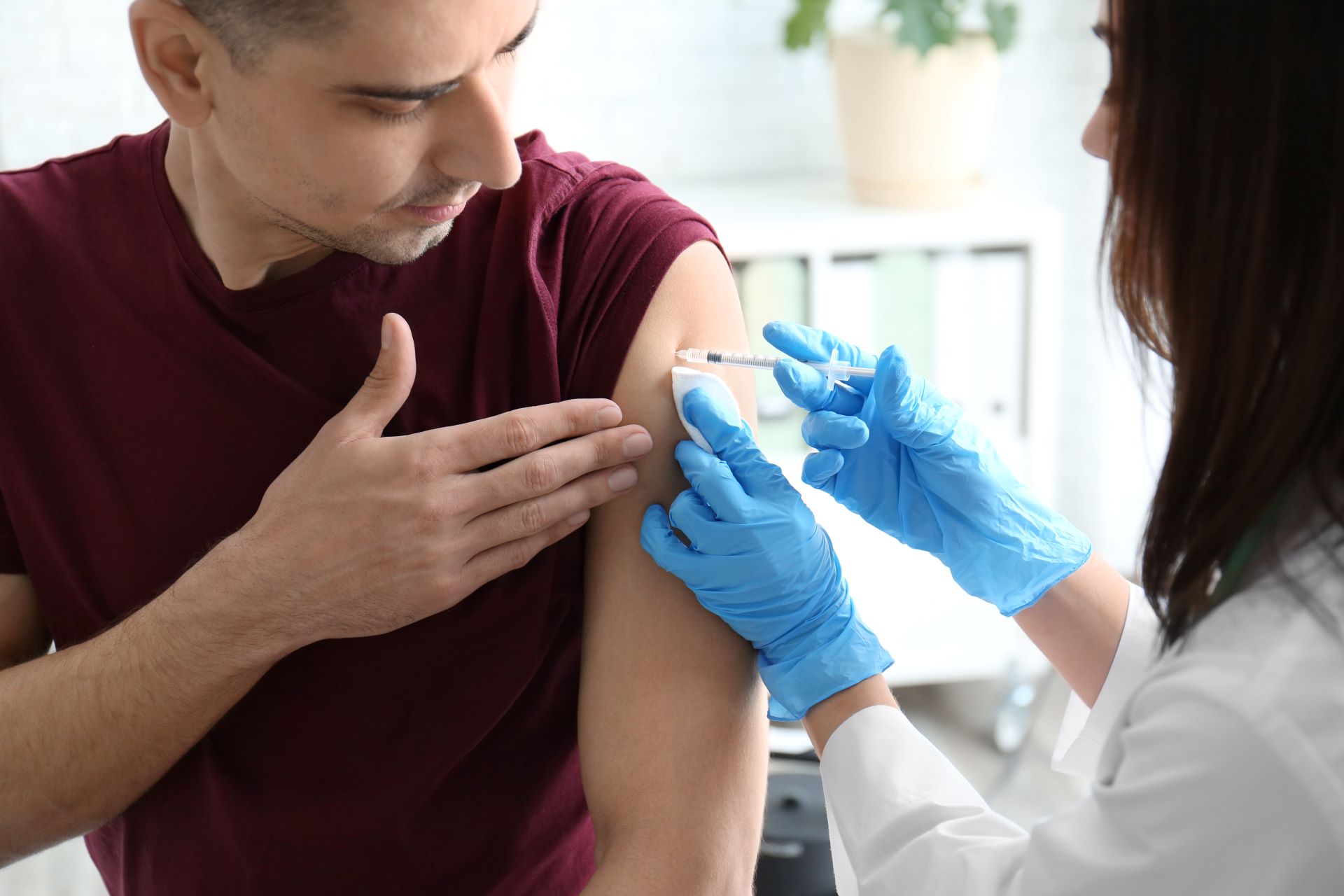 Doctor vaccinating male patient in clinic